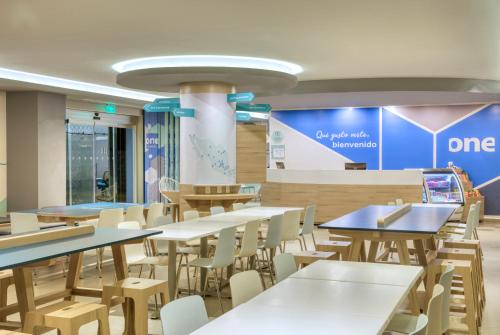 a dining area with tables and chairs in a cafeteria at One Tapachula in Tapachula