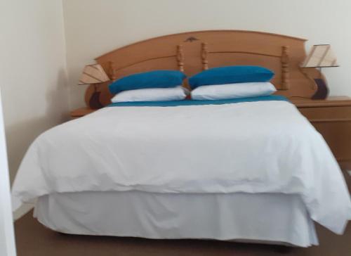 a bed with blue and white pillows on it at Liz' Cottage in Mbabane