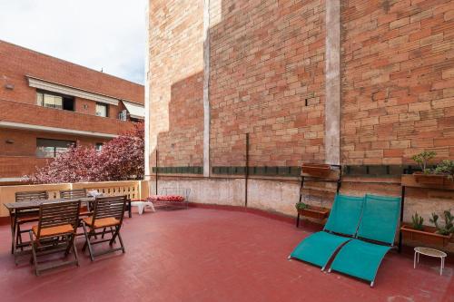 un patio con sillas, una mesa y un edificio de ladrillo en Monlau 12, en Barcelona