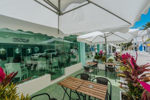 une terrasse avec un banc en bois, des tables et des parasols dans l'établissement Green Coast Beach Hotel, à Punta Cana