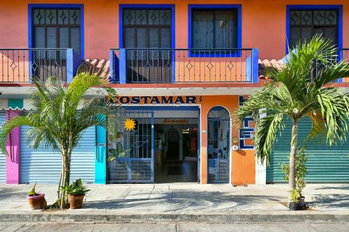 een kleurrijk gebouw met palmbomen ervoor bij Hotel Costamar, Puerto Escondido in Puerto Escondido