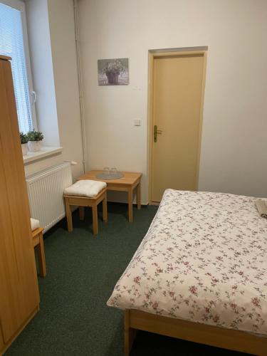 a room with a bed and a table and a door at Penzion Ječmínek in Luhačovice