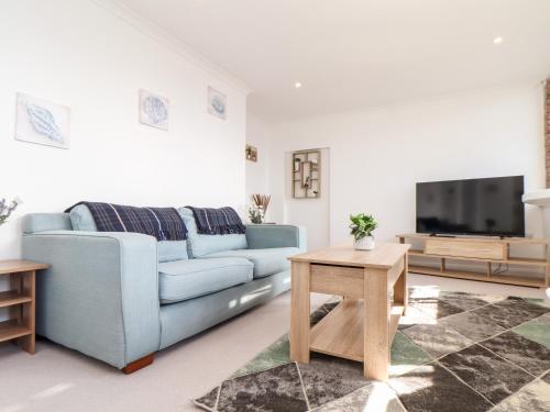 a living room with a blue couch and a tv at Lighthouse Lofts - Godrevy in Camborne