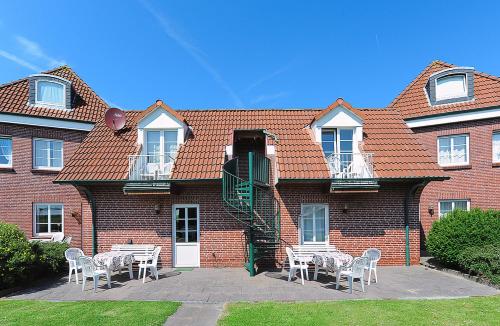 un bâtiment en briques avec des tables et des chaises devant lui dans l'établissement Ferienhaus Wattn Urlaub, à Bensersiel