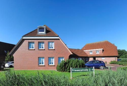 une maison en briques avec un panneau devant elle dans l'établissement Ferienhaus Wattn Urlaub, à Bensersiel