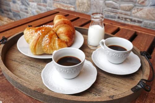 two cups of coffee and croissants on a wooden table at C'era una volta in Castelnuovo Don Bosco