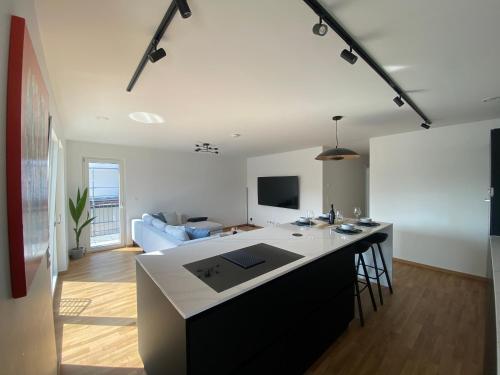 eine Küche und ein Wohnzimmer mit einer Theke und einer Couch in der Unterkunft Strassen - 2 bed designer flat in Strassen