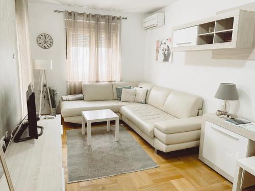 uma sala de estar branca com um sofá e uma mesa em Aurora Apartment em Podgorica