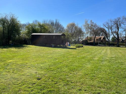 een groot grasveld met een gebouw op de achtergrond bij Pipowagen voor 4 personen in Diever