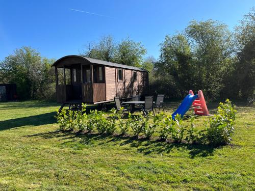 een klein huisje in een veld met een speeltuin bij Pipowagen voor 4 personen in Diever