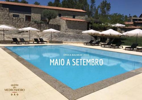 einem Pool mit Stühlen und Sonnenschirmen vor einem Gebäude in der Unterkunft Quinta do Medronheiro Hotel Rural in Viseu