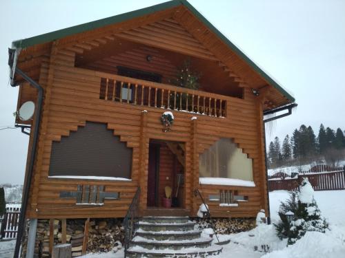 a log cabin in the snow with a balcony at Вілла Олекси in Skhidnitsa