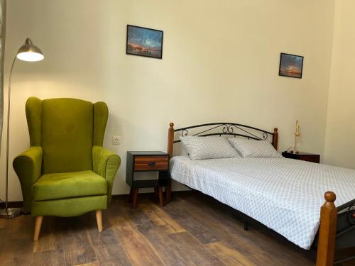 - une chambre avec un lit et une chaise verte dans l'établissement Prista guest rooms, à Ruse