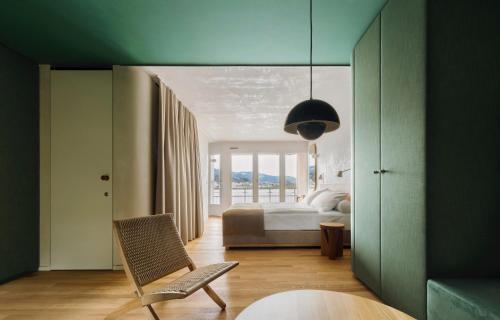 a bedroom with a bed and a chair in it at HERMITAGE Lake Lucerne - Beach Club & Lifestyle Hotel in Luzern