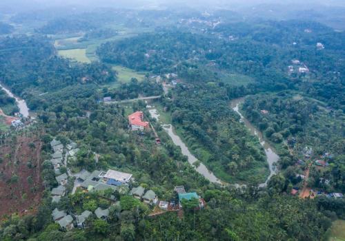 an aerial view of a river and houses and trees at Great Trails Wayanad by GRT Hotels in Wayanad