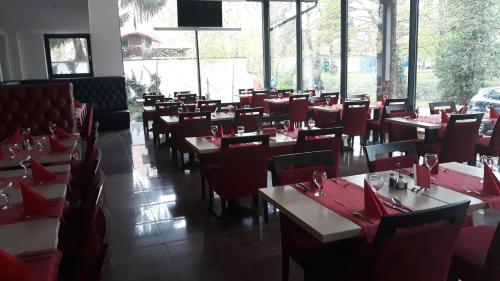 a restaurant with red tables and chairs and windows at Mátyás Apartmanház in Gyula