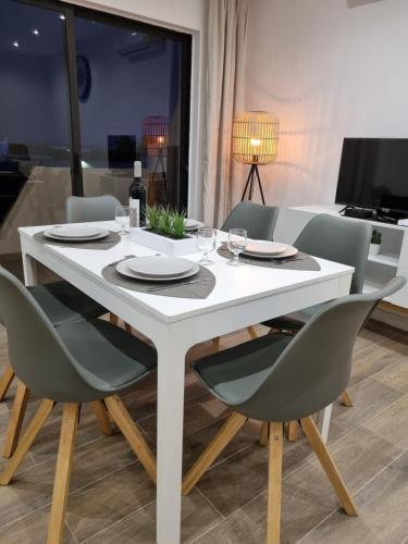 een witte eettafel en stoelen met een witte tafel en een stoeltje bij Rosamar in Alvor