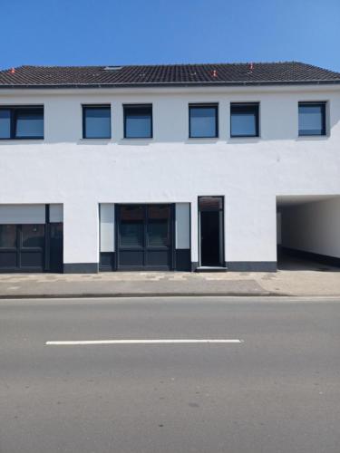 um edifício branco com portas pretas e uma rua em kleines boardinghouse em Nordwalde