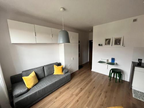 uma sala de estar com um sofá cinzento e almofadas amarelas em Apartament Love Góry Karpacz Centrum em Karpacz