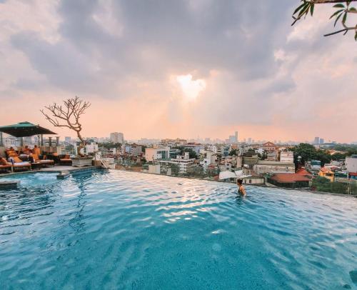 un homme dans une piscine avec une ville en arrière-plan dans l'établissement Peridot Grand Luxury Boutique Hotel, à Hanoï