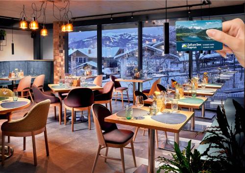 a person taking a picture of a dining room with tables and chairs at ever grün KAPRUN in Kaprun