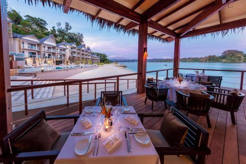 um restaurante com mesas e cadeiras com vista para a água em Ramada Resort by Wyndham Port Vila em Port Vila