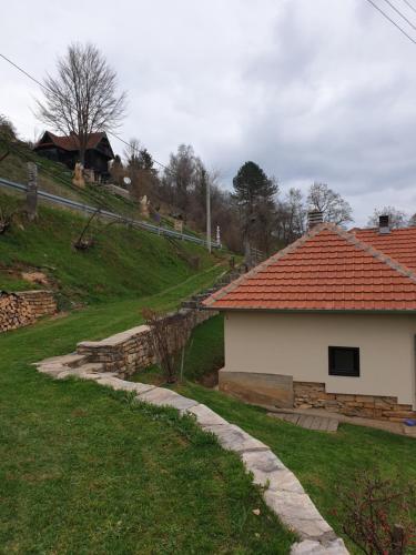 uma casa com um telhado de azulejos laranja ao lado de um quintal em Kuća za odmor - Martić, Rudno, Golija em Kraljevo