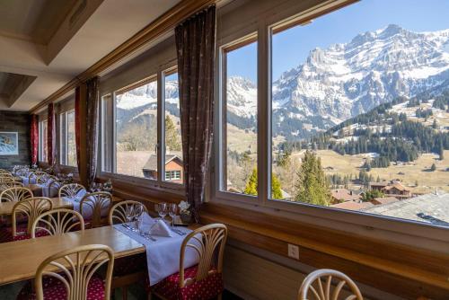 ein Restaurant mit einem Tisch und Stühlen sowie Bergblick in der Unterkunft Chalet-Hotel Beau-Site in Adelboden