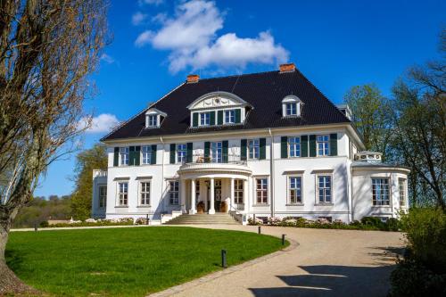 una gran casa blanca con techo negro en Hotel Gut Immenhof, en Malente