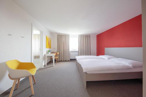 um quarto de hotel com duas camas e uma cadeira amarela em Le Domaine (Swiss Lodge) em Fribourg