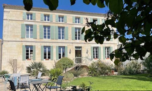 a building with a table and chairs in front of it at La Tillaie SPA et Sauna in Pont-lʼAbbé-dʼArnoult