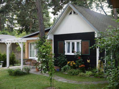 a small black and white house with a porch at Ferienhaus Püttbergeweg, Berlin in Berlin