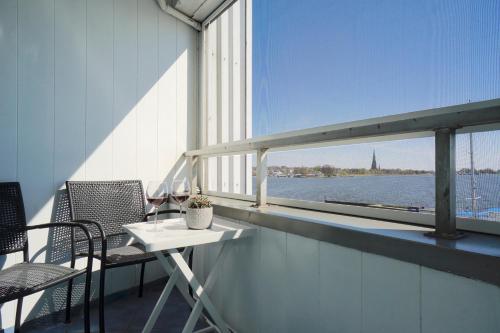 Ferienwohnung Schleiloge mit Panoramablick auf die Schlei في شلسفيغ: طاولة وكراسي على شرفة مطلة على الماء