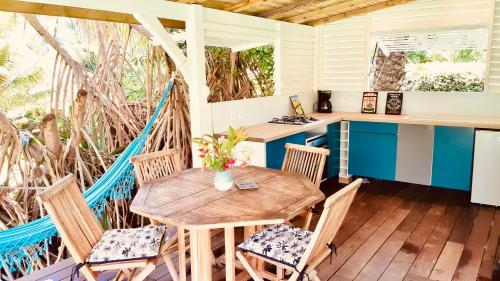 een veranda met een houten tafel en stoelen bij Villa Gaïa - Bungalow Ti-Zen et son jacuzzi niché dans un jardin tropical, séjour en amoureux in Le Diamant