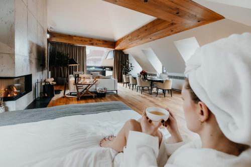 Eine Frau, die in einem Bett mit einer Tasse Kaffee sitzt. in der Unterkunft DO & CO Hotel München in München