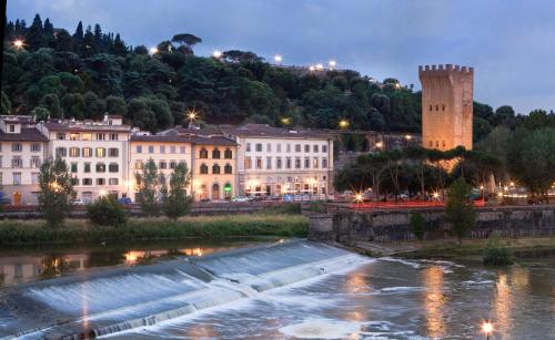 une ville de nuit avec une rivière et des bâtiments dans l'établissement LHP Hotel River & SPA, à Florence