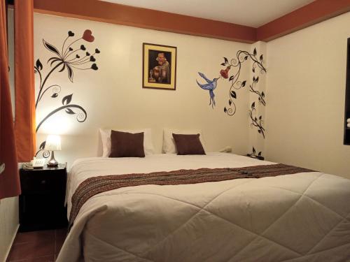 - une chambre avec un lit orné de fleurs sur le mur dans l'établissement Inkas Land, à Machu Picchu