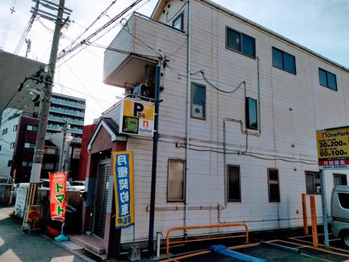 een wit gebouw met borden aan de zijkant bij Osaka Tomato Guesthouse in Osaka