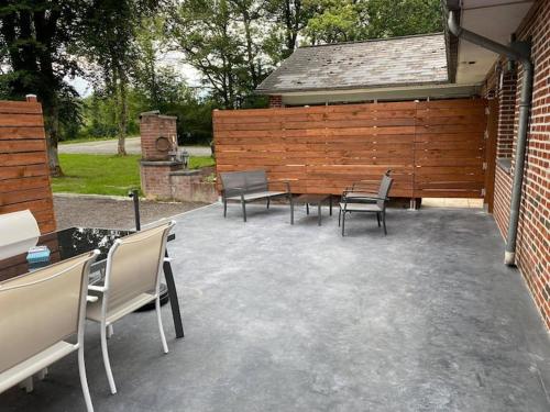 une terrasse avec des chaises et des tables ainsi qu'une clôture en bois. dans l'établissement GITE DE LA FAMENNE, à Marche-en-Famenne