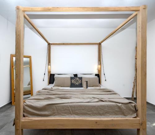 een houten hemelbed in een slaapkamer met een spiegel bij Casa Naturale in Skopelos Town