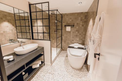 een badkamer met een toilet, een wastafel en een bad bij Hostellerie Cèdre & Spa Beaune in Beaune