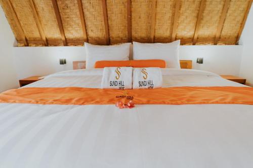 um quarto com uma cama branca com duas toalhas em Sundi Hill Cottage em Nusa Penida