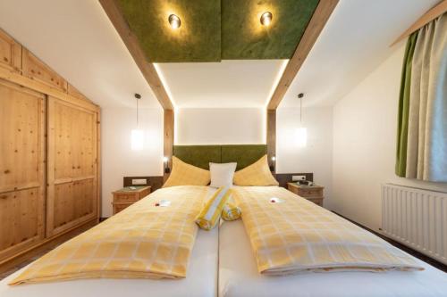 1 dormitorio con 1 cama blanca grande con almohadas amarillas en Hotel Sporthof Austria, en Ramsau am Dachstein