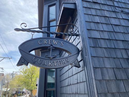 a sign for a greenys quarters on the side of a building at Crew's Quarters Boarding House - Caters to Men in Provincetown