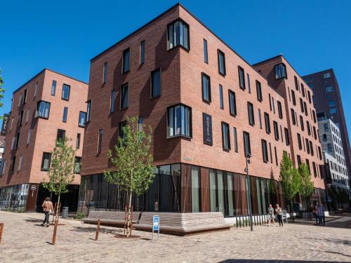 a large brick building with people walking in front of it at Hotel Odeon in Odense