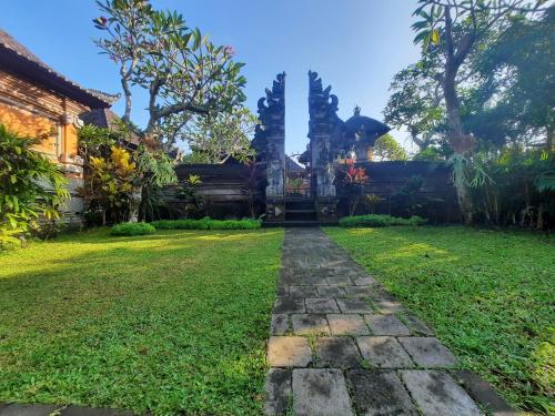 un jardín con un camino de piedra frente a un edificio en Sahadewa House, en Ubud