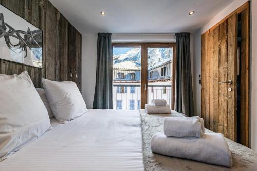 una camera da letto con un grande letto bianco e una finestra di Le Globe Argentière Chamonix - by EMERALD STAY a Chamonix-Mont-Blanc