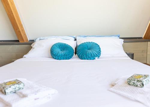 two blue pillows sitting on a white bed at Glamping Gli Etruschi in Piombino