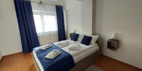 een slaapkamer met een groot bed en blauwe gordijnen bij Andi Apartment in Sibiu