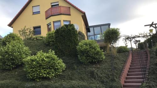 ein gelbes Haus auf einem Hügel mit Büschen in der Unterkunft Ferienwohnung Le in Adenau